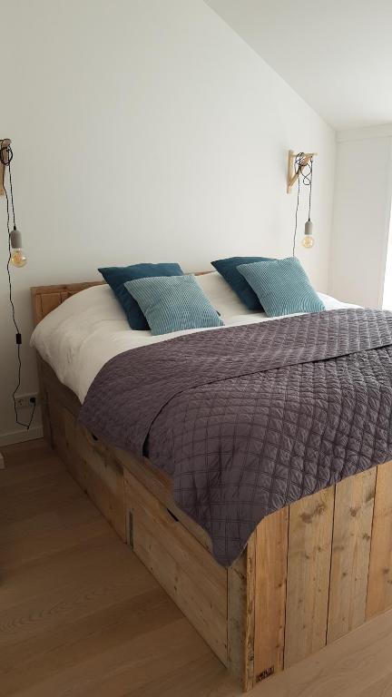 een houten bed met twee blauwe kussens erop bij Prachtige woning aan de duinen in Den Helder