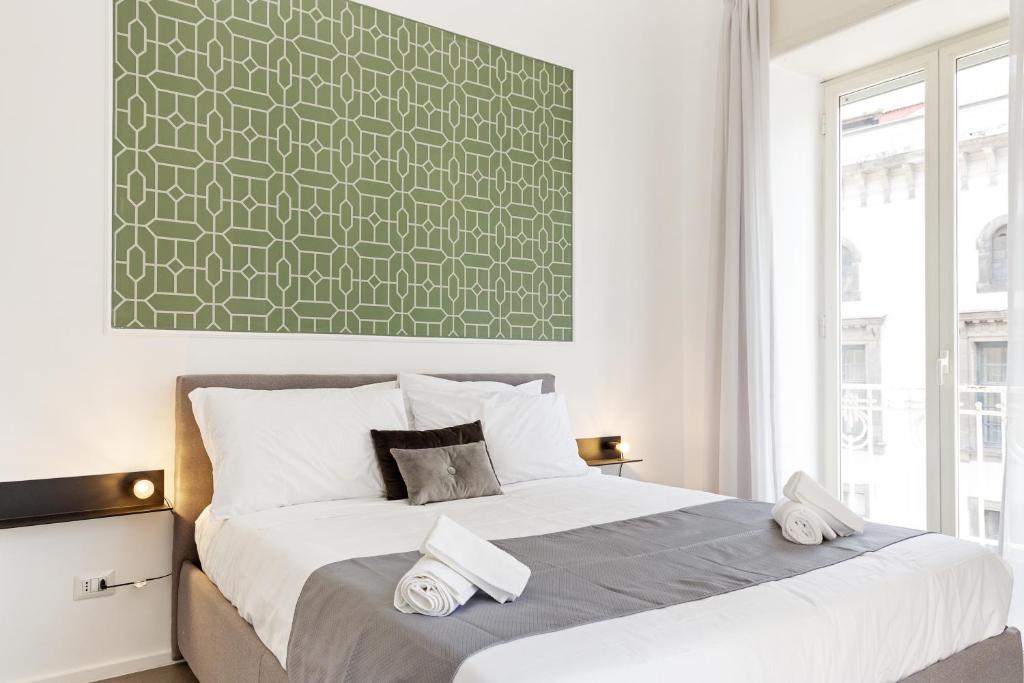 1 dormitorio con 1 cama grande y pared verde en Napoli Suite Caravaggio Apartment, en Nápoles
