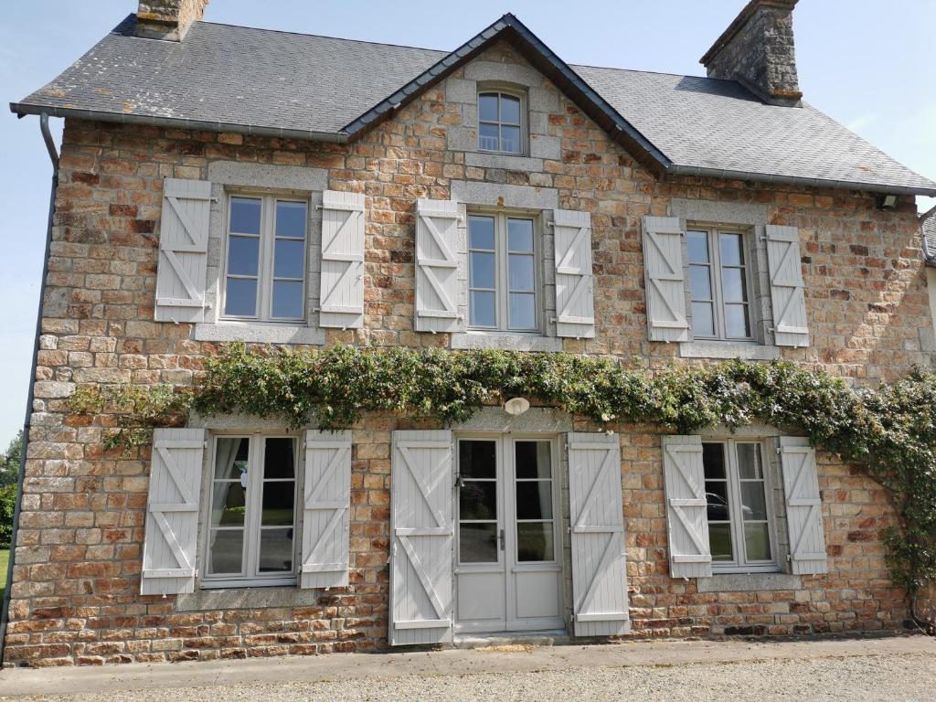 a brick house with white windows and ivy at La Vallée in Saint-Pierre-Langers