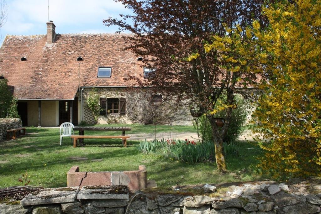 um edifício de pedra com um banco à frente em Le Petit Mingot em Druy-Parigny