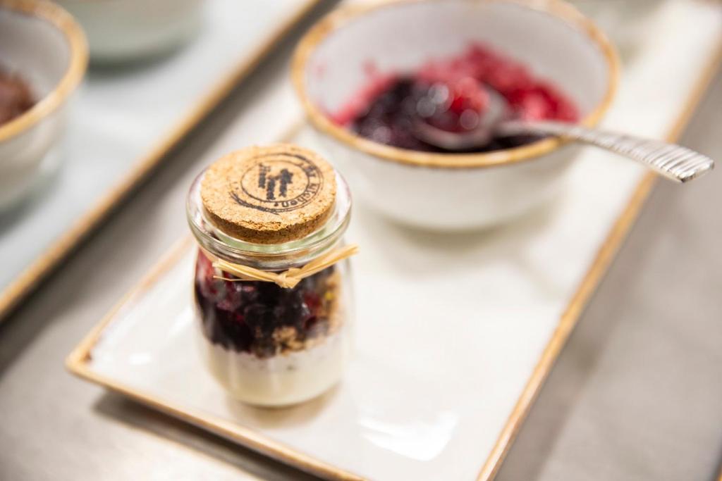 a jar of jam on a plate with a bowl of fruit at 1926 Le Soleil Hotel & Spa in Sliema