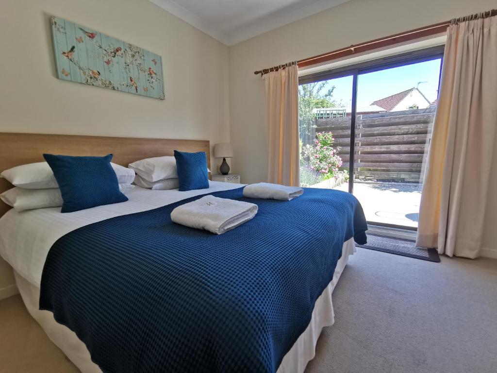 a bedroom with a large bed with blue sheets and a window at Hazeldene Apartment Unit in Perth