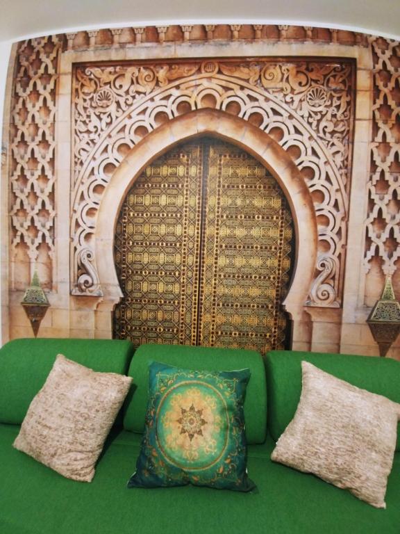 eine grüne Couch mit Kissen vor einer Wand in der Unterkunft Weltenhaus in Unterumbach