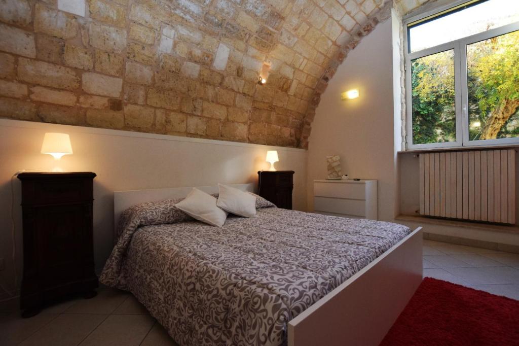ラグーザにあるLe Fioriere Affittacamere e Casa vacanzeのレンガの壁、ベッド付きのベッドルーム1室