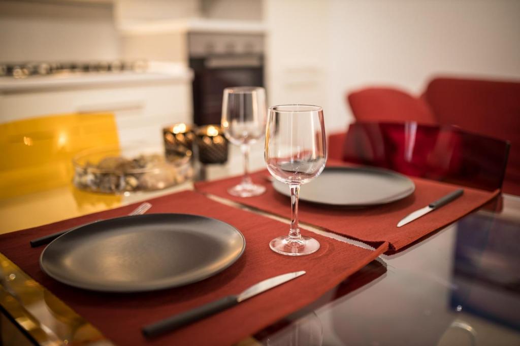 einen Tisch mit zwei leeren Tellern und Weingläsern in der Unterkunft La Casa di Manu Ortigia in Syrakus
