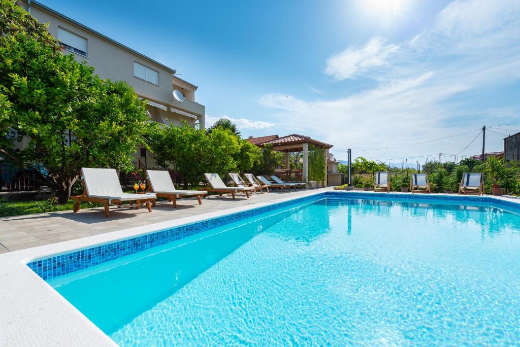 una piscina con sedie a sdraio accanto a un edificio di Villa Apartments Duje a Kaštela (Castelli)