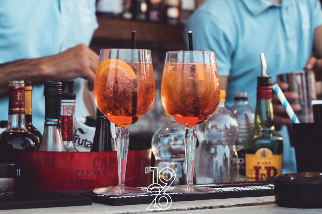 two glasses of wine on a bar with bottles of alcohol at 1926 Le Soleil Hotel & Spa in Sliema