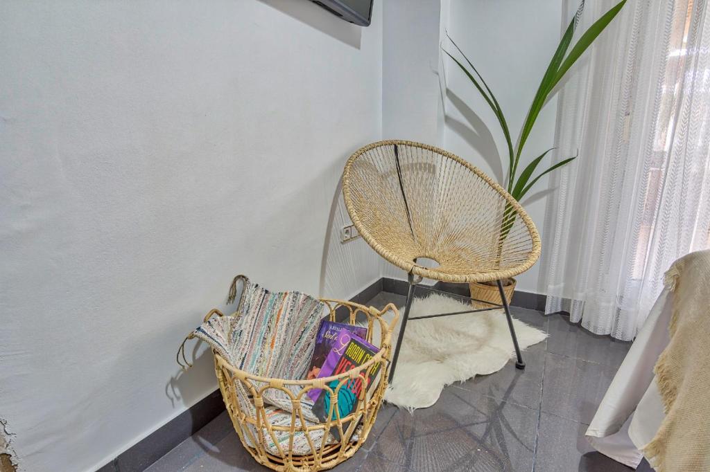 a rattan chair next to a basket of magazines at ROOMQUEO-Only Adults in Barbate