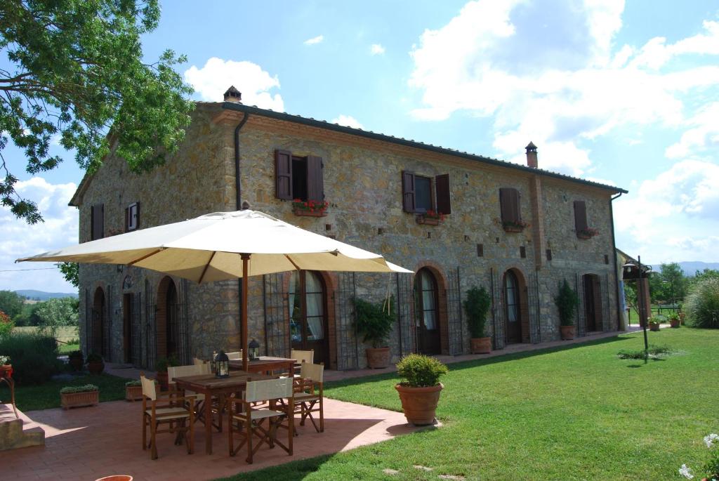 a table with an umbrella in front of a building at Podere i Melograni in Guardistallo