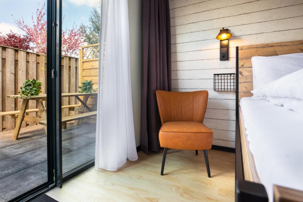 a bedroom with a bed and a chair on a balcony at Hotel De Kroon in Kaatsheuvel