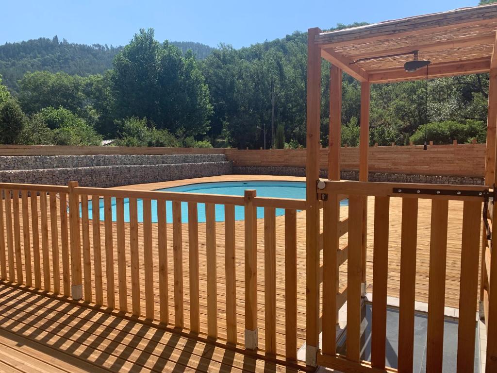 une terrasse en bois avec une piscine et une pergola dans l'établissement Camping du Bourg, à Digne-Les-Bains