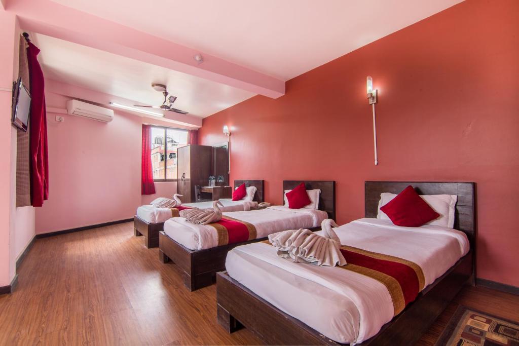 three beds in a room with red walls at Hotel Family Home in Kathmandu
