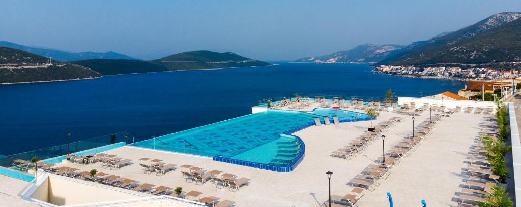 a large swimming pool with chairs and a body of water at Grand Hotel Neum Wellness & Spa in Neum