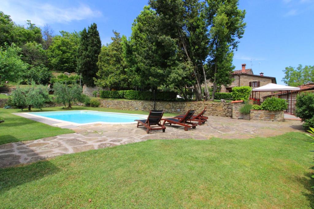 Un patio trasero con piscina y dos tumbonas. en Casa Ciabatti, en Castel Focognano