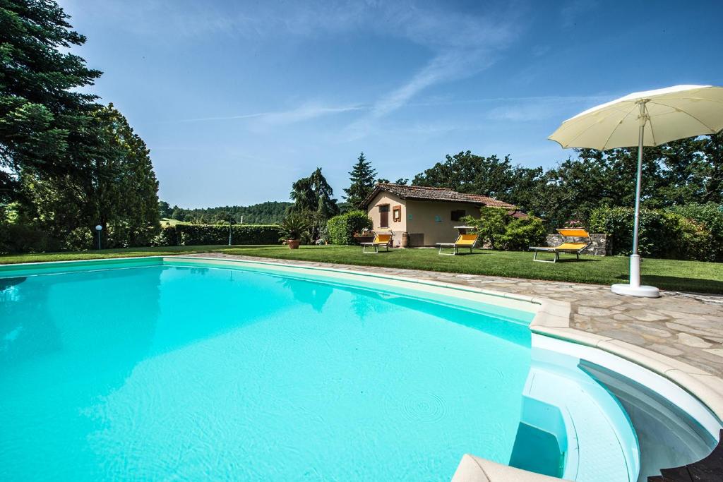 a large blue swimming pool with an umbrella at Agriturismo Podere La Fornace in Cavriglia