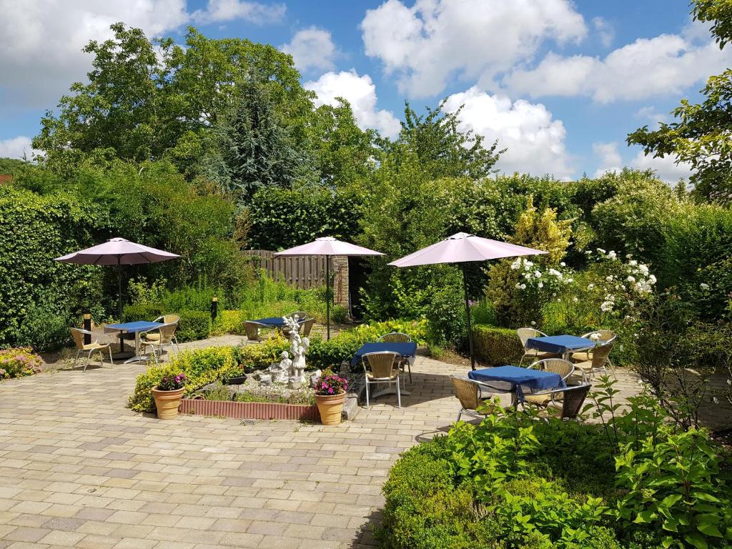 eine Terrasse mit Tischen und Sonnenschirmen im Garten in der Unterkunft Hotel Le Provencal in Sluis