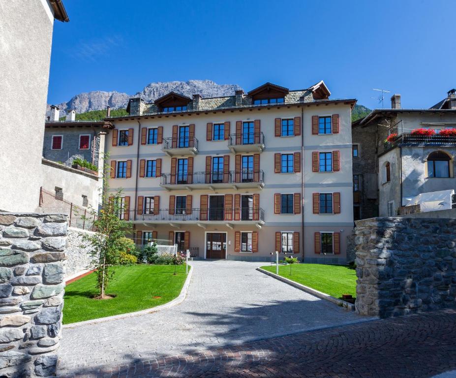 a large white building with a mountain in the background at HOTEL AD Residence in Bormio
