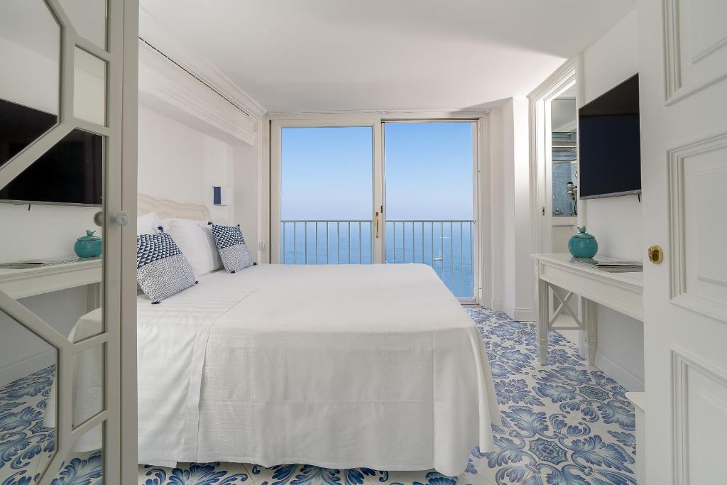 a bedroom with a white bed and a large window at Piazzetta Diefenbach in Capri