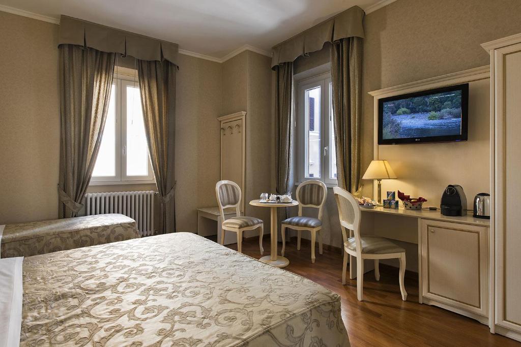una camera d'albergo con letto, scrivania e sedie di Relais Bocca di Leone a Roma