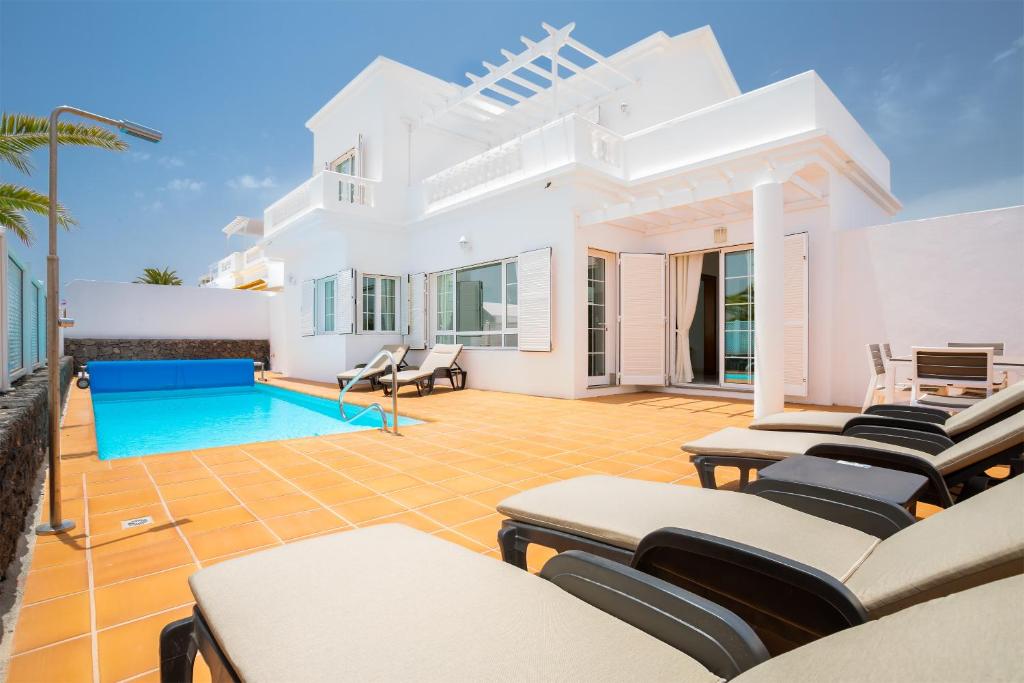 a villa with a swimming pool and lounge chairs at Villa Felicidad in Puerto del Carmen