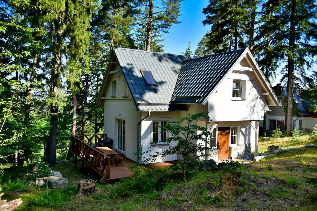 a small white house with a porch in the woods at Górski Domek koło Karpacza- Apartamentuj in Karpacz