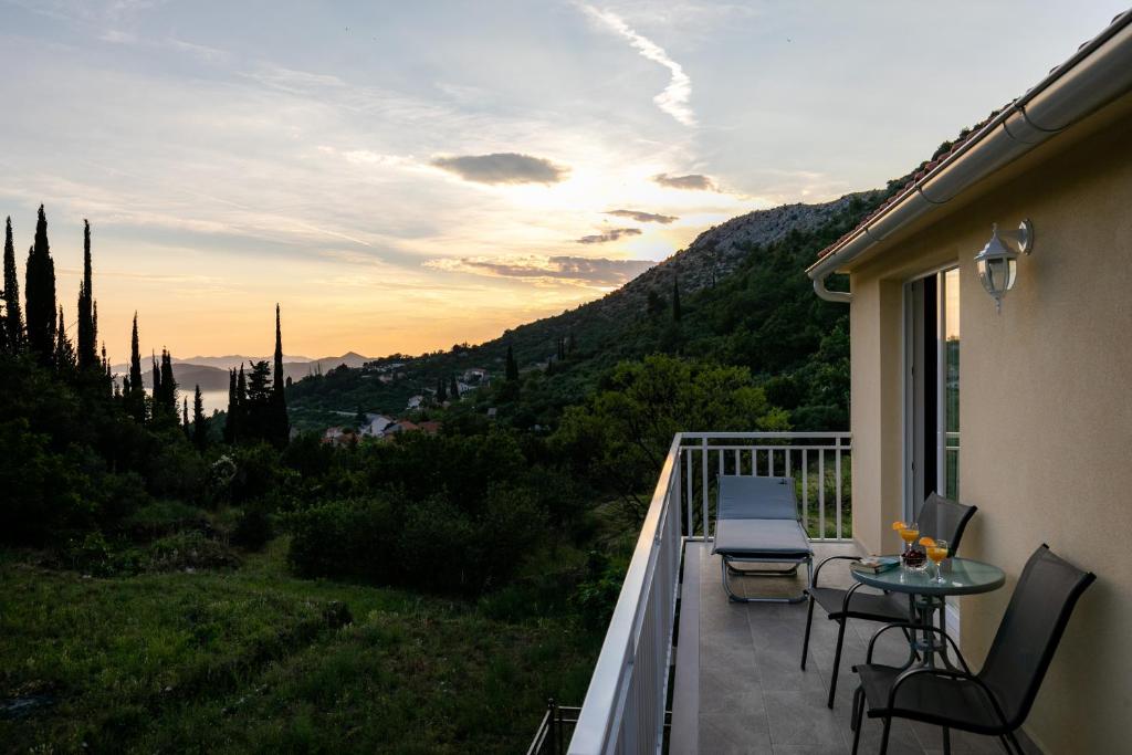 a balcony with a table and chairs and the sunset at Relax Zone Apartment in Trsteno