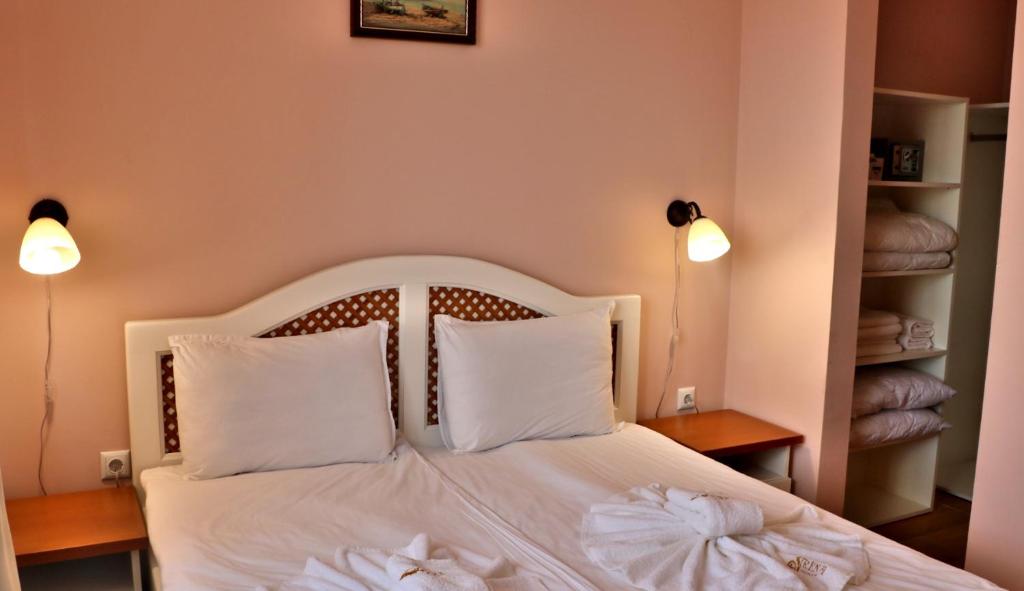 a bedroom with a bed with white sheets and pillows at Sirena Palace Family Hotel in Obzor
