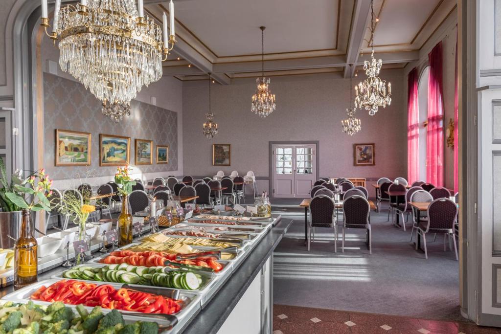 uma linha de buffet numa sala de jantar com lustres em First Hotel Statt Örnsköldsvik em Örnsköldsvik