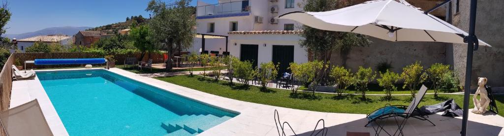 Pinos del Valle的住宿－Casa los tejones，一座带遮阳伞的游泳池位于大楼旁
