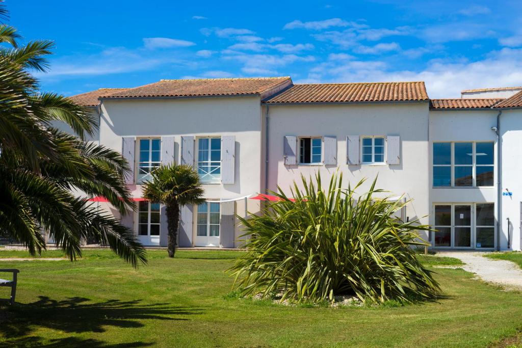 a house with palm trees in front of it at Thalacap Île de Ré - Thalasso & Spa in Ars-en-Ré