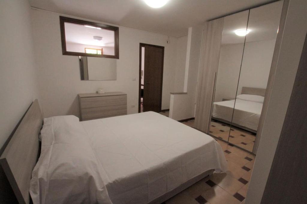 1 dormitorio con cama blanca y espejo en Casetta delle Arti, en Mondragone