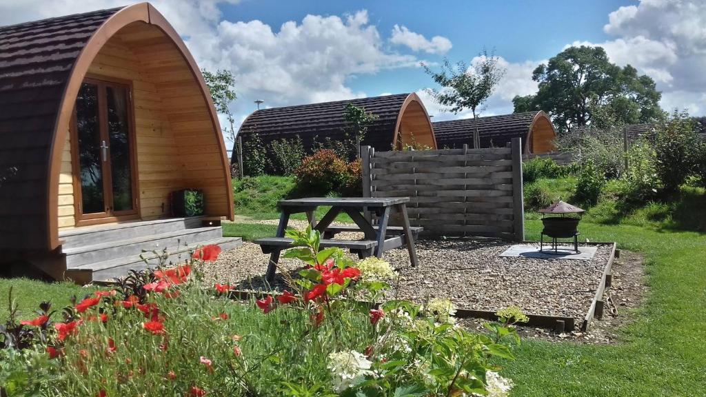 a garden with a picnic table and a cabin at Willowherb Glamping Pod in Cheltenham