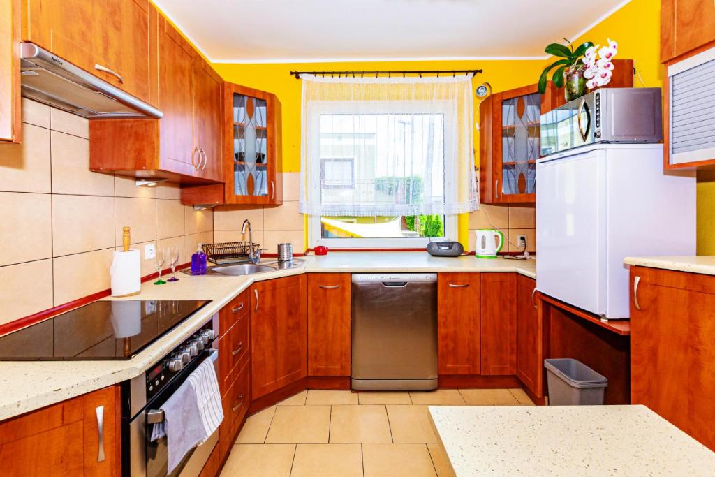 a kitchen with wooden cabinets and a white refrigerator at Apartamenty Maciejka in Władysławowo