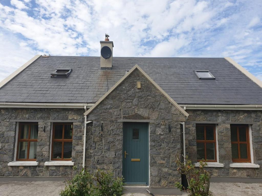 une maison en pierre avec une porte bleue dans l'établissement Shannon's House, à Doolin