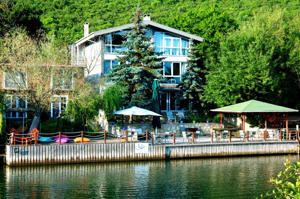 a hotel with tables and umbrellas next to the water at Agva Nehir Evi - Adult Only in Ağva