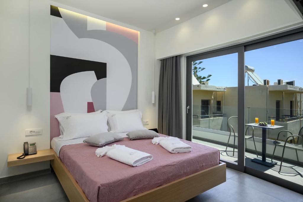 a bedroom with a large bed and a balcony at Athina Suites Luxury Suites Near The Sea Platanias in Platanias