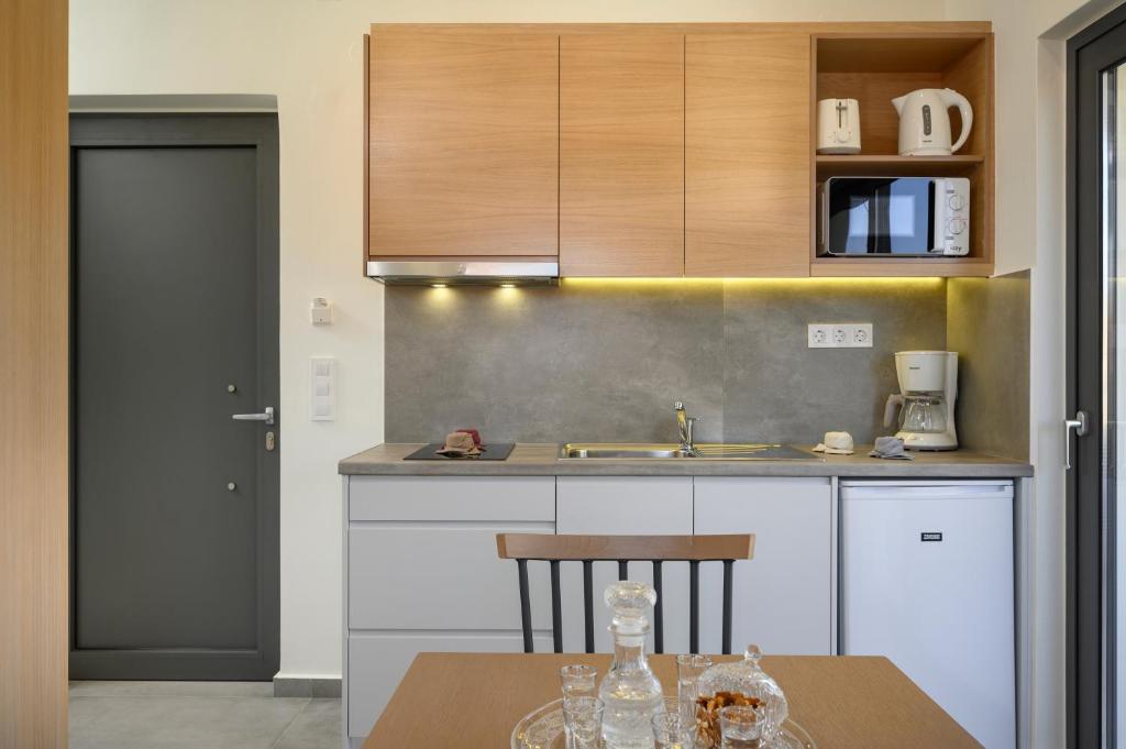 a kitchen with white cabinets and a table with chairs at Athina Suites Luxury Suites Near The Sea Platanias in Platanias