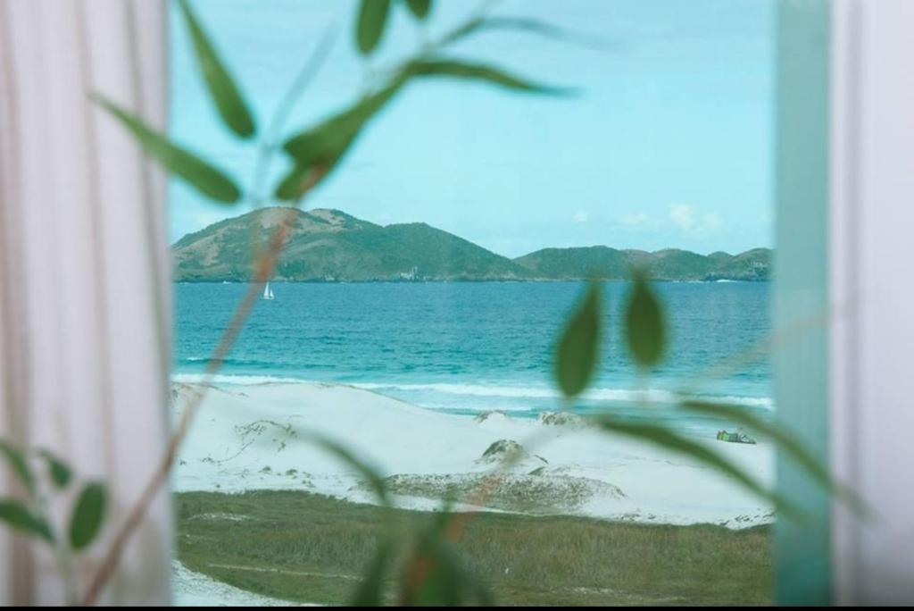 a view of a beach with the ocean and mountains at Cabo Frio frente Mar 03qt in Cabo Frio