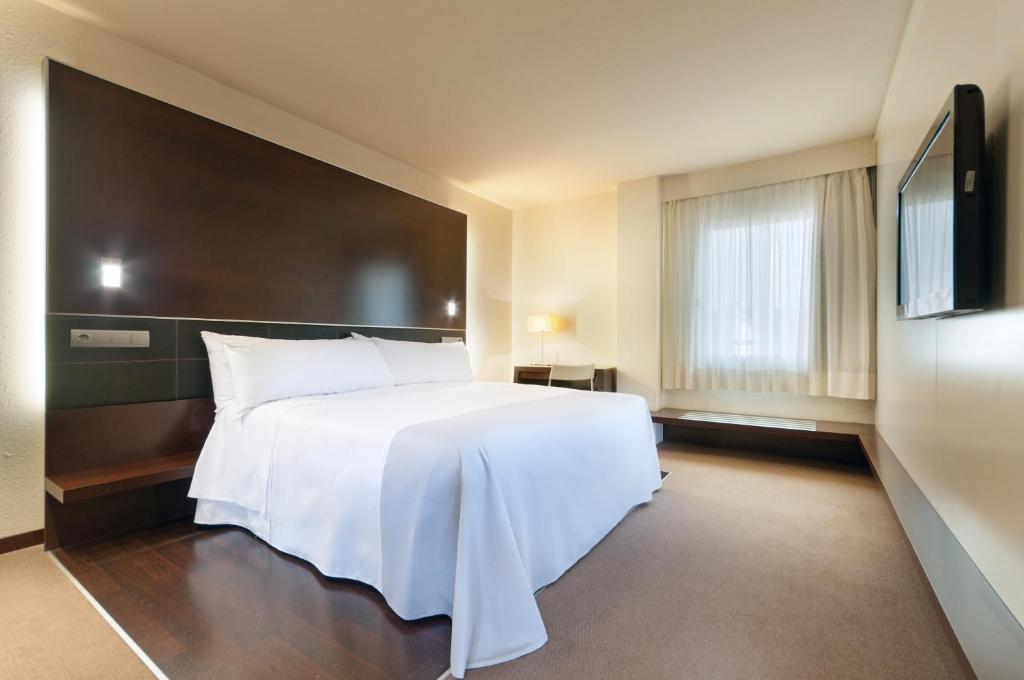 a bedroom with a white bed and a flat screen tv at Hotel Ceuta Puerta de Africa in Ceuta