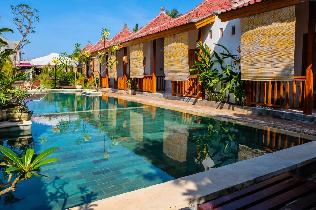 a swimming pool in front of a house at Bungalow And Restaurant Anda in Kuta Lombok