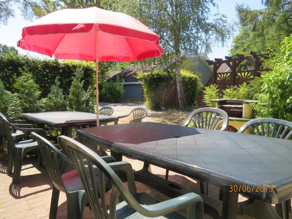 a patio table with a red umbrella and chairs at -Waldhaus-Fewo 4 in Granzow