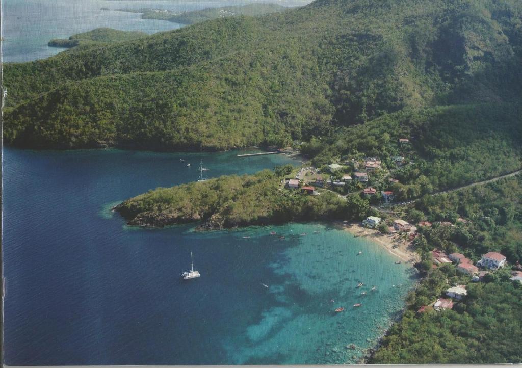 an island with a sail boat in the water at Domaine de Robinson in Les Anses-dʼArlets