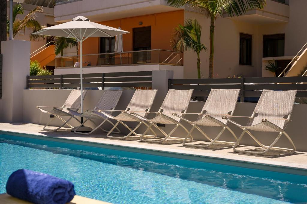 a group of chairs and an umbrella next to a swimming pool at Athina Suites Luxury Suites Near The Sea Platanias in Platanias