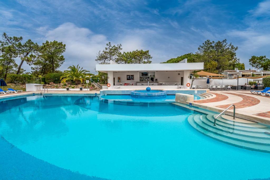 a swimming pool with blue water in a resort at BmyGuest - Quinta do Lago Garden Apartment in Almancil