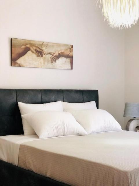 a bedroom with a bed with white sheets and a chandelier at Sofimel Apartment in Skala Sotiros