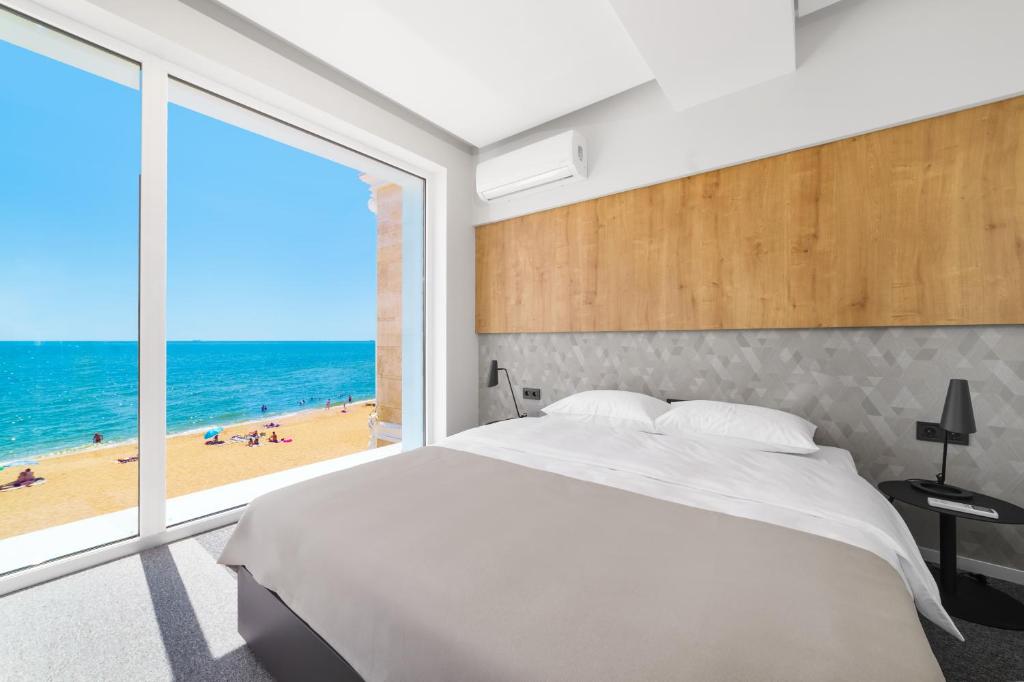 a bedroom with a large bed and a view of the beach at Poseidon Deluxe перша лінія з басейном in Odesa