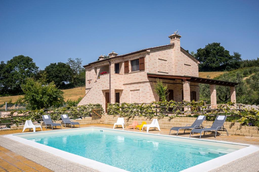 a swimming pool with chairs and a house at Sottocastello Il Casale in Osimo