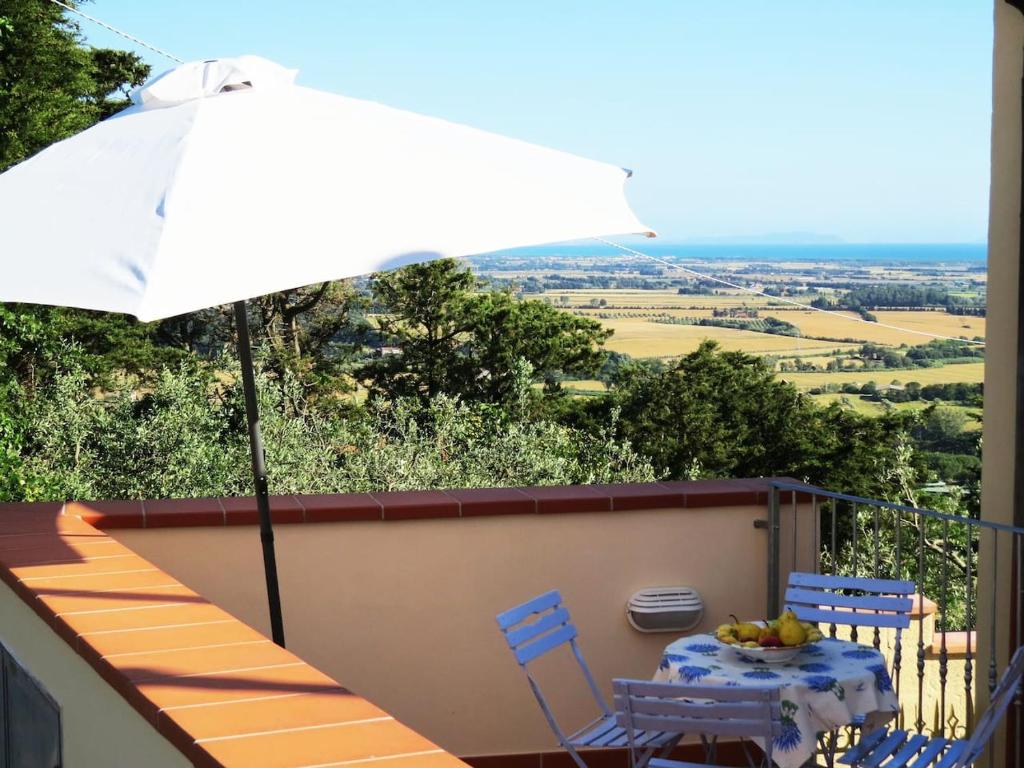 stół i krzesła z parasolem na balkonie w obiekcie L'Orizzonte di Nocchi Manrico w mieście Rosignano Marittimo