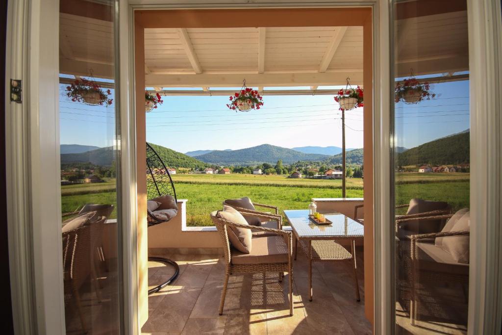 a porch with a table and a view of a field at Holiday house Leona in Otočac
