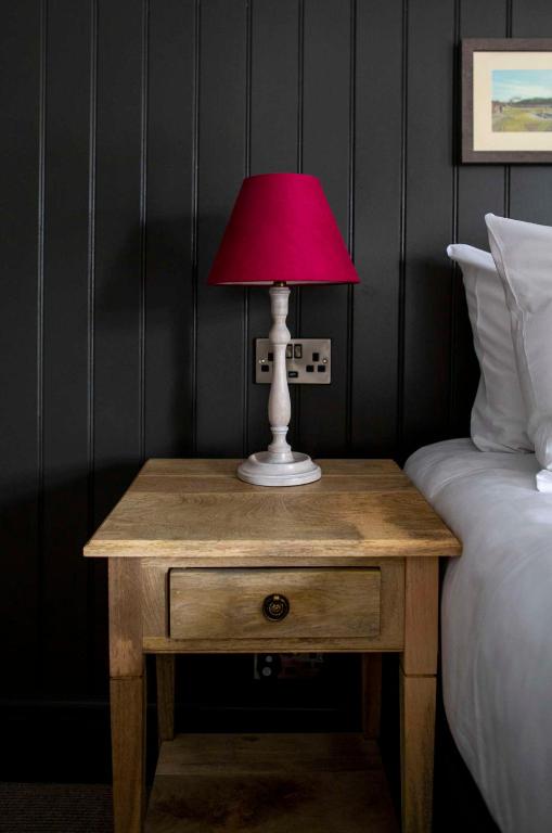 a table with a lamp on it next to a bed at Dunstan House in Burnham on Sea